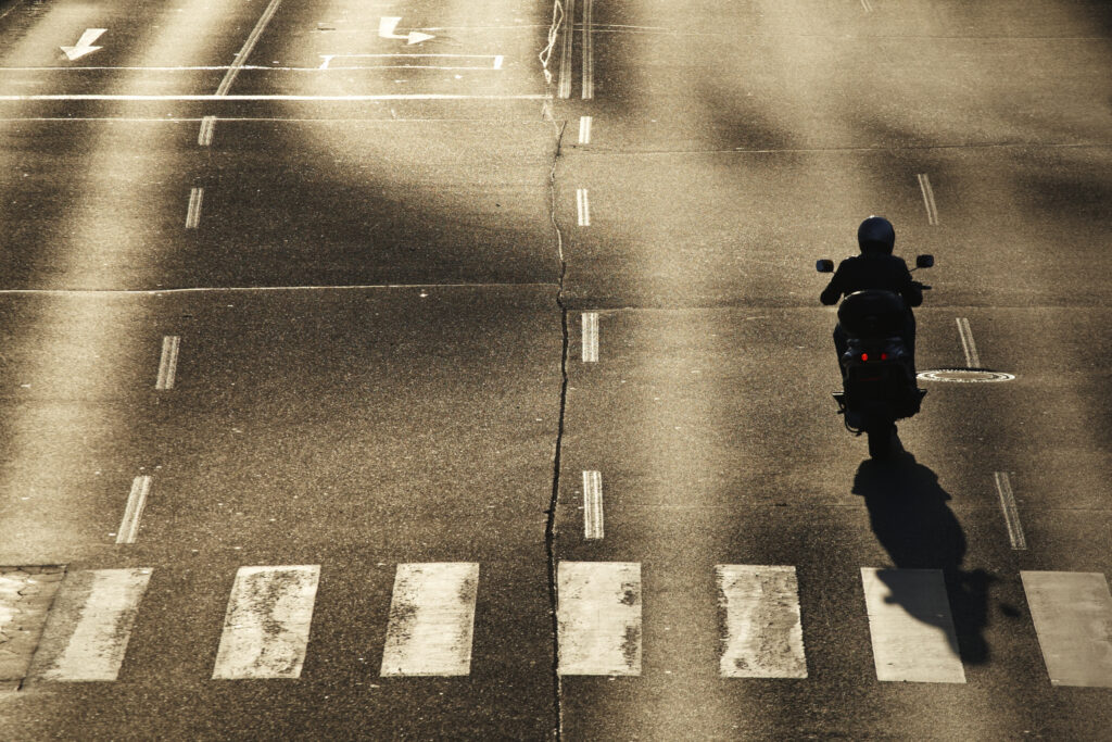 single motorcyclist in the middle of the crossroad at sunset